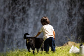 大きな滝でペットの犬を持つ若い女の子の背面図