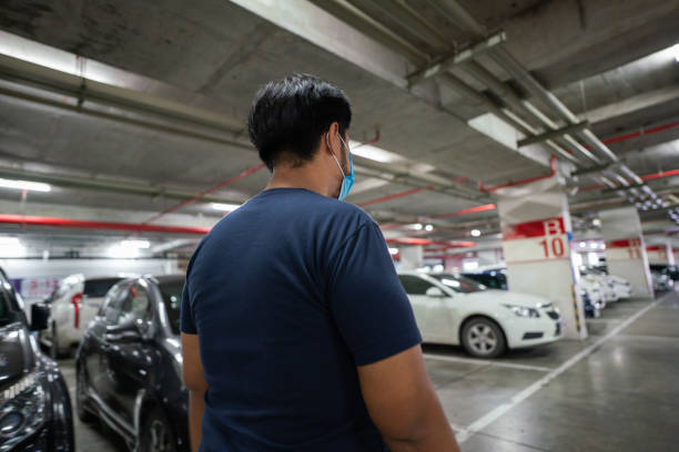 Rear view of Asian man walking in underground parking lot stock photo