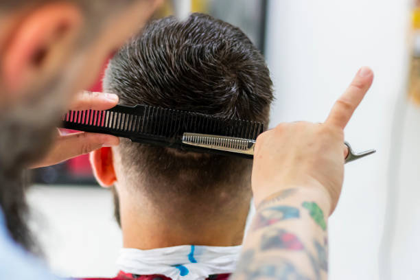 Rear view of barber cutting hair with thinning scissors stock photo