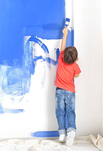 Rear View Of Boy Painting Wall stock photo