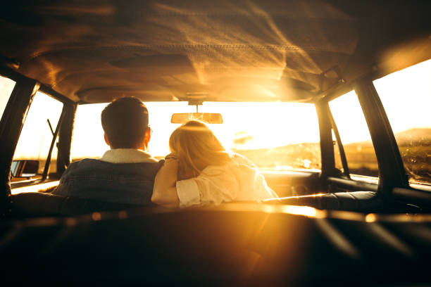 Rear view of couple in car Romantic , young couple driving in car on sunny evening, embracing and enjoying, rear view, photo is taken in car from 1980 year mid adult couple stock pictures, royalty-free photos & images