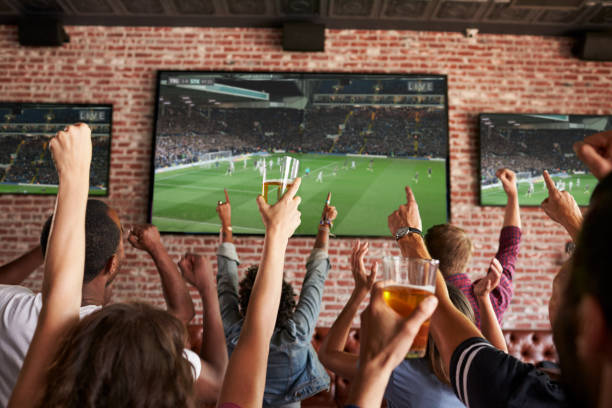 rear view of friends watching game in sports bar on screens - desporto imagens e fotografias de stock