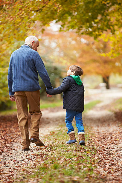 vista traseira do avô e neto a caminhar ao longo do caminho - grandparents vertical imagens e fotografias de stock