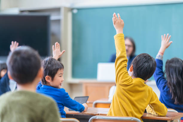 手を挙げながら学童群の背面図 - 日本 ストックフォトと画像