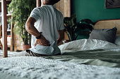 istock Rear view of senior Asian man suffering from backache, massaging aching muscles while sitting on bed. Elderly and health issues concept 1354565595