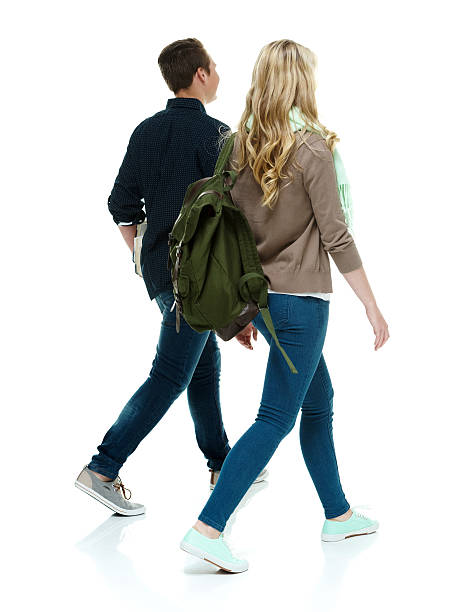 Rear view of two students walking together stock photo