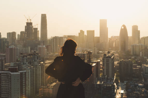 Rear view of Woman looking at city in Sunlight stock photo