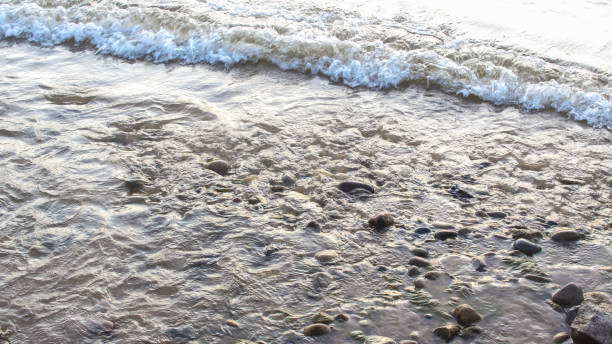Receding waves leave rocky beach stock photo