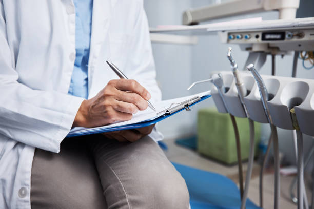 I recommend a daily dose of good dental hygiene Shot of an unrecognisable dentist writing notes on a piece of paper dental equipment stock pictures, royalty-free photos & images