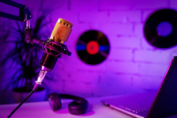recording podcast - microphone headphones and laptop in home studio. neon lights stock photo