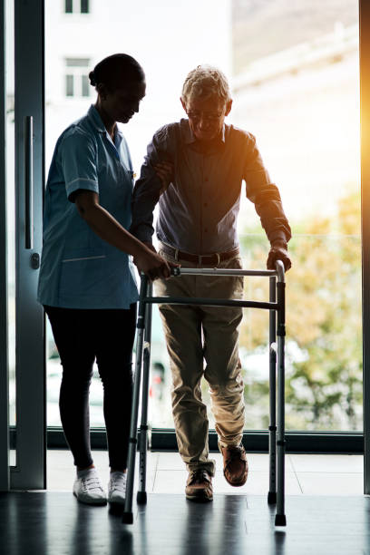 Recovery begins with one step Shot of a young nurse helping a senior man with a walker osteoporosis photos stock pictures, royalty-free photos & images