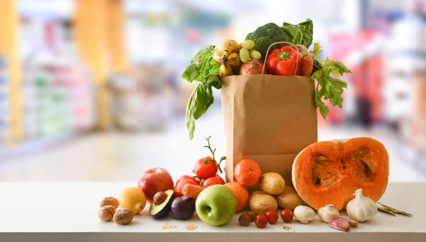Recyclable shopping bag with fruits and vegetables with supermarket background stock photo