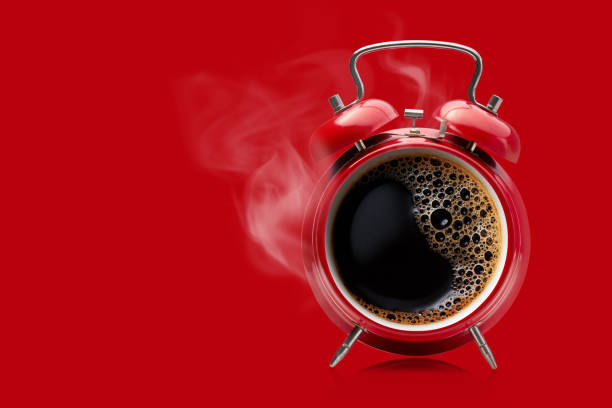 Red alarm clock with hot black coffee. Hot coffee in a retro alarm clock. Wake up alarm coffee concept. morning stock pictures, royalty-free photos & images