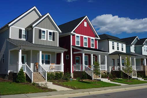 Street view of a row of houses.  The front of each house has a porch, stairs and a sidewalk.