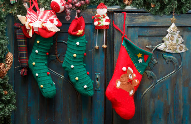 Red and green stockings, evergreen branch with pine cones and christmas toys on blue doors of old wardrobe. stock photo