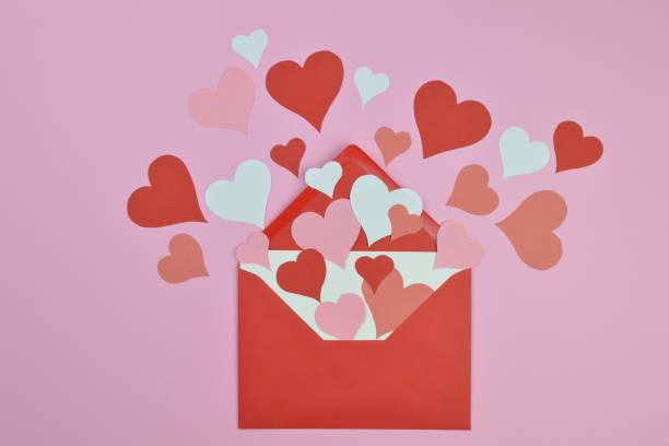 red and pink paper hearts in an red envelope on pink stock photo