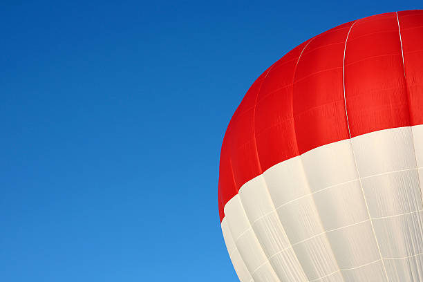 Red and White Hot Air Balloon Extreme Close up of a red and white top of an inflated hot air balloon with a blue summer sky background.  Sky leaves blank area for copyspace. zero gravity carnival ride stock pictures, royalty-free photos & images