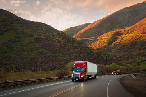 Red and white semi-truck driving in Utah mountain range