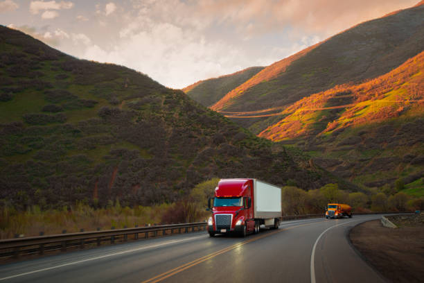 Red and white semi-truck driving in Utah mountain range stock photo