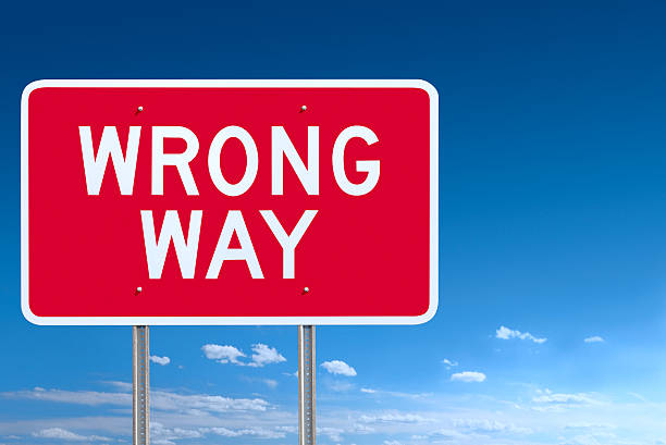 Red and White Wrong Way Road Sign Post Over Sky stock photo