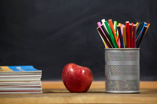 red apple, books and penciles on wooden table and blackdoard background.school for kids. stock photo