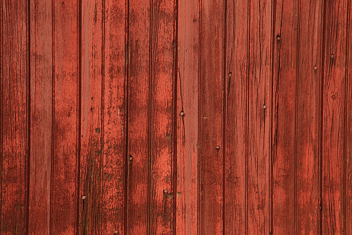 Deep red wooden barn siding vertical background with rough texture.