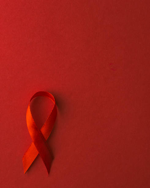 símbolo de la cinta de arco rojo vih, concienciación sobre el cáncer de sida con sombras, toma de estudio aislada sobre fondo rojo, concepto de medicina sanitaria, día mundial del sida - world aids day fotografías e imágenes de stock