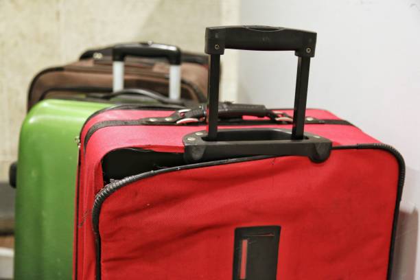 Red broken traveling luggage, crack and torn at the corner with other baggage in background, at the airport. Need to be repaired and claimed the airline  broken suitcase stock pictures, royalty-free photos & images
