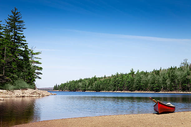 Red canoe stationed on a lake shore stock photo