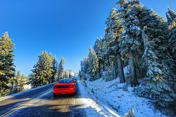 Red car on snowy and icy winter road stock photo
