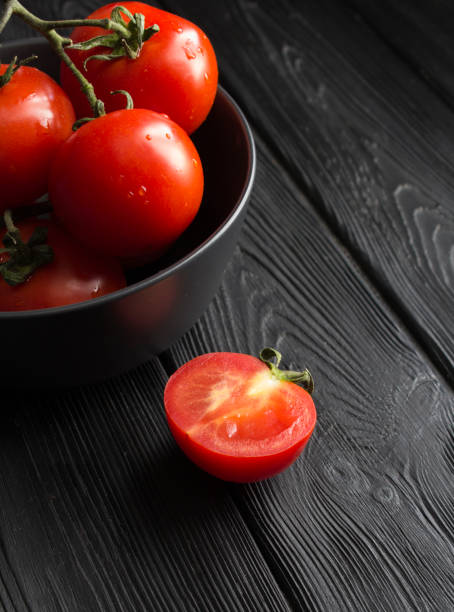 Red cherry  tomato on the black wooden background. Close-up. stock photo