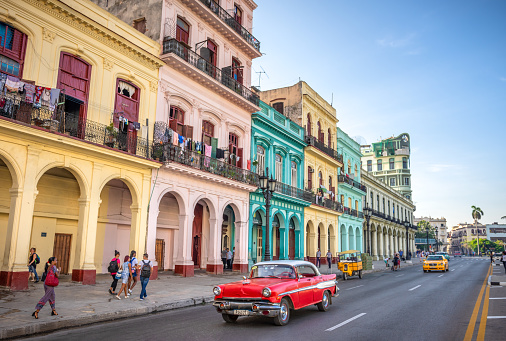 August 1, 2018 - La Havana, Cuba: red classic car and a yellow taxi in the colorful streets of la Havana, Cuba