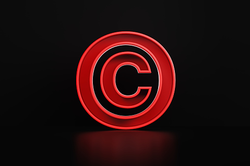 Red copyright  symbol sitting on before black background. Horizontal composition with copy space.