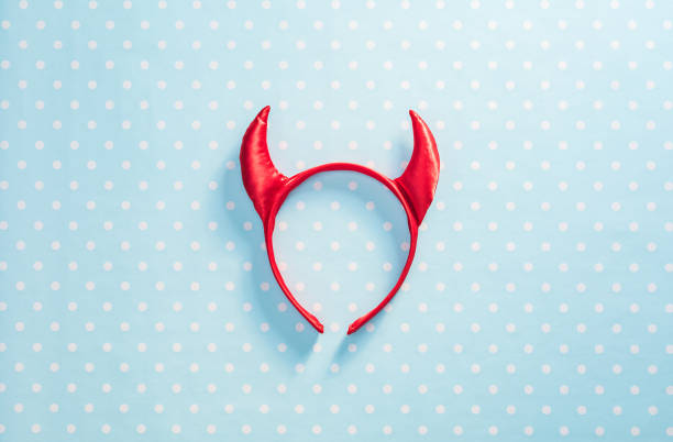Red devil horns on a headband hoop. Halloween texture background stock photo