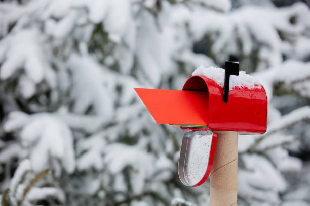 Red envelope in mailbox in a snow near pine tree in winter stock photo