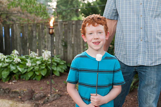 Red headed boy prepares to cook his marshmallow stock photo