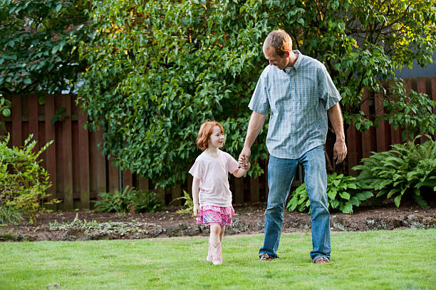 Red headed girl walking with her father. stock photo