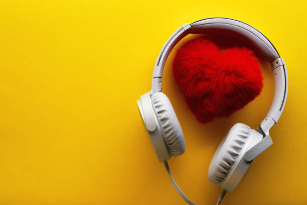 hati merah dan headphone putih pada latar belakang kuning. suka konsep gaya hidup musik. hari valentine - hear sad sing potret stok, foto, & gambar bebas royalti