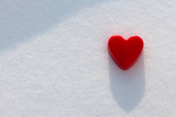 Red heart in the snow with sunshine stock photo