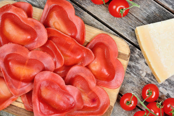 Red heart ravioli with parmesan on a wood table stock photo