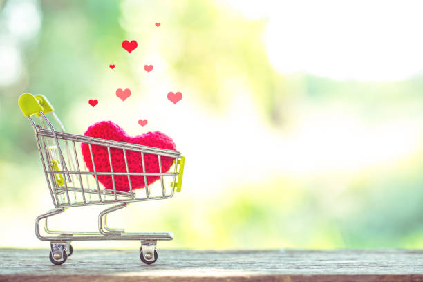 red heart shape on mini shopping cart over wooden background. Image for happy valentine day concept. stock photo