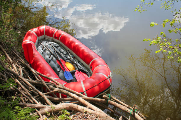 Red inflatable boat with oars (raft) for rafting along a  river against the sky reflected in the water. View from above stock photo