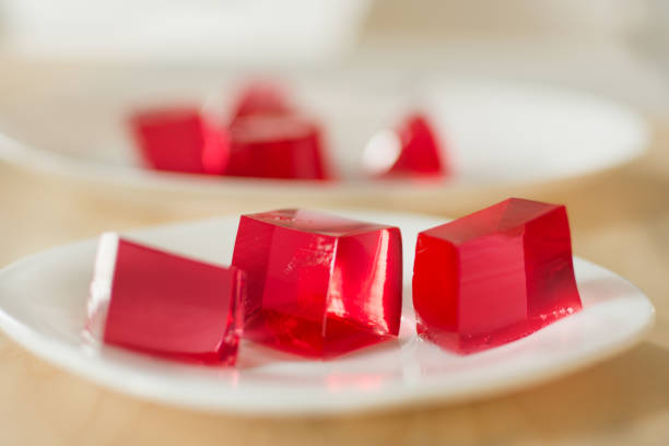 Red jelly cubes on white plate background. Berry sweet pieces of jelly. Homemade red cherry gelatin dessert. gelatin dessert stock pictures, royalty-free photos & images