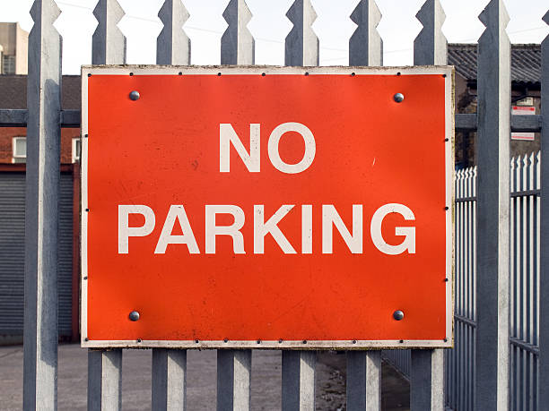 Red No Parking sign on metal fence stock photo