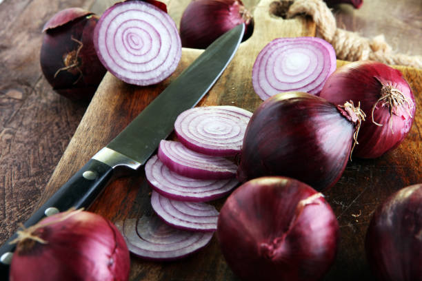 Red onions circles and red onions on board against wooden background stock photo