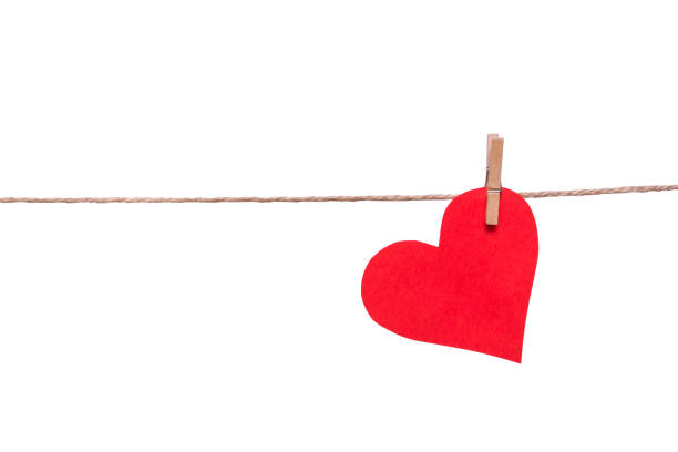 Red paper heart and clothespin on a rope isolated on white background. stock photo