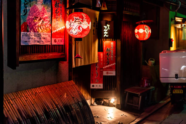 Red paper lanterns glowing with geisha poster in dark night with nobody at entrance to restaurant stock photo
