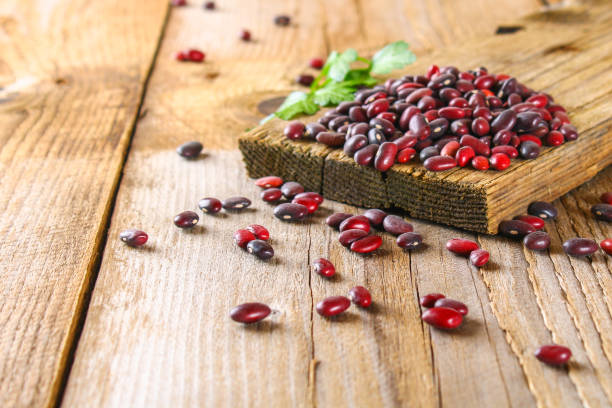 Red raw beans with greens on a wooden table. stock photo