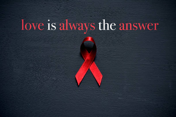 red ribbon and text love is always the answer a red ribbon for the fight against AIDS and the text love is always the answer on a dark gray surface world aids day stock pictures, royalty-free photos & images