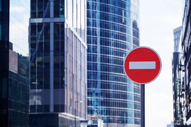 Red road stop sign or brick on city skyscrapers business center blurred background close up, entrance prohibition, restriction or no way symbol, no entry allowed or forbidden traffic sign, copy space stock photo